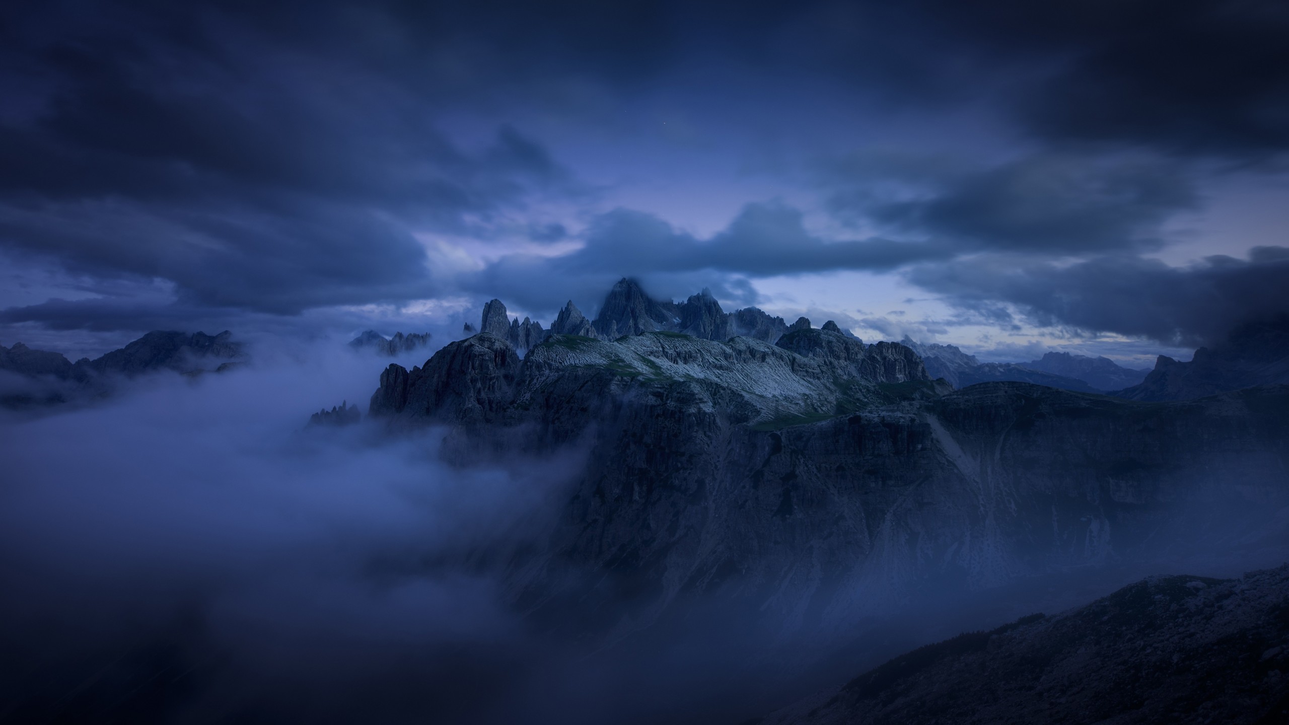 A dark mountain surrounded by clouds